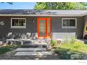 Modern gray house with an orange front door and small deck at 7705 Baseline Rd, Boulder, CO 80303