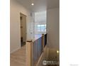 Bright hallway with wood floors and black metal railing at 731 Kubat Ln # A, Longmont, CO 80503