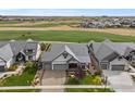 Stunning aerial view showcases the house, a lush golf course, and the neighborhood's beautiful landscaping at 2920 Heron Lakes Pkwy, Berthoud, CO 80513