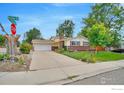 Quaint home featuring manicured front yard, brick accents, and attached two-car garage on a tree-lined street at 1638 Meeker Dr, Longmont, CO 80504