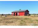Red barn with white trim and metal roof, complemented by a fenced pasture at 10691 County Road 23, Fort Lupton, CO 80621