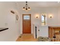 Welcoming entryway featuring a stylish front door, hardwood floors, and decorative lighting at 10691 County Road 23, Fort Lupton, CO 80621