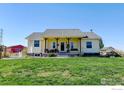 Charming home with a welcoming front porch, yellow siding, and well-manicured lawn at 10691 County Road 23, Fort Lupton, CO 80621