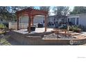 Charming backyard with a wooden pergola, brick retaining wall, and lovely landscaping, great for outdoor living at 10635 County Road 24, Fort Lupton, CO 80621