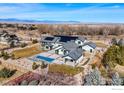 Expansive aerial view of home with solar panels, pool, and lush surroundings against a mountain backdrop at 9258 Niwot Hills Dr, Niwot, CO 80503