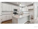 Modern kitchen with white cabinets, a large island, and stainless steel appliances at 2787 Optimista Pl, Brighton, CO 80601