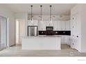 Modern white kitchen with a center island, stainless steel appliances, and pendant lighting at 1581 Poplar Dr, Erie, CO 80516