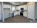 Bright kitchen with stainless steel appliances, white cabinets, and hardwood floors at 2263 Serenidad St, Brighton, CO 80601