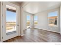 Bright living room featuring hardwood floors, large windows with scenic views, and a glass patio door at 2277 Serenidad St, Brighton, CO 80601