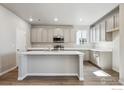 Bright kitchen featuring a central island, stainless steel appliances, and lots of gray cabinets for storage at 2283 Serenidad St, Brighton, CO 80601