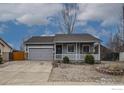 Charming single-story home with gray siding, a covered front porch, gray garage door and low maintenance landscaping at 3557 Settler Ridge Dr, Mead, CO 80542