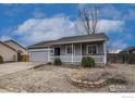 Charming single-story home with gray siding, a covered front porch, gray garage door and low maintenance landscaping at 3557 Settler Ridge Dr, Mead, CO 80542