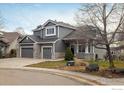 Two-story house with gray siding, stone accents, and a three-car garage at 1366 Teton Pt, Lafayette, CO 80026