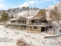 Contemporary home boasts a spacious deck, hot tub, and serene mountain backdrop in a snow-covered setting at 230 Cactus Ct, Boulder, CO 80304