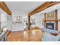 Open-concept living room with a brick fireplace, wooden beams, and hardwood floors connecting seamlessly to the kitchen at 160 Bristlecone Way, Boulder, CO 80304