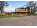 Rustic two-story home with a detached shed and gravel driveway at 12645 Foothills Hwy, Longmont, CO 80503