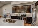 Stainless steel appliances and dark brown cabinets in kitchen at 410 High Point Dr # 203, Longmont, CO 80504