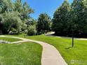 A concrete walking path through a well maintained green lawn with mature trees and manicured landscaping at 5540 Stonewall Pl # 16, Boulder, CO 80303