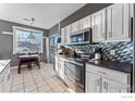 Modern kitchen with white cabinets, stainless steel appliances, and a breakfast bar at 12953 Lafayette St # C, Thornton, CO 80241