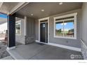 Inviting front porch showcasing gray siding, stone accents, and a modern black front door at 1369 Burt Ave, Berthoud, CO 80513