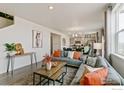 Open concept living room with gray couch and orange pillows, and kitchen in background at 2236 Crosswind St, Fort Lupton, CO 80621