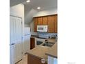 Modern kitchen with wood cabinets, white appliances, and a double sink at 3101 Iron Forge Pl # J-206, Boulder, CO 80301