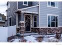 Front entrance of townhome with stone accents and a snowy walkway at 5108 Buckwheat Rd, Brighton, CO 80640