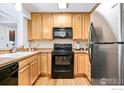 Kitchen with wood cabinets, black appliances, and wood floors at 6545 Kalua Rd # 203D, Boulder, CO 80301