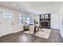 Bright and airy living room with a fireplace, large windows, and hardwood floors at 1040 Hoover Ave, Fort Lupton, CO 80621