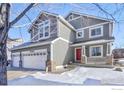 Two-story house with gray siding, a red front door, and a three-car garage at 4964 Shenandoah Ave, Firestone, CO 80504