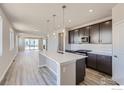 Open concept kitchen with island, dark cabinets, and white backsplash at 2957 South Flat Cir, Longmont, CO 80503