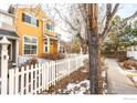 Two-story yellow home with white picket fence and walkway at 911 Snowberry St, Longmont, CO 80503