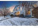 Two-story townhome with light gray siding, snowy front yard, and landscaping at 1419 Red Mountain Dr # 13, Longmont, CO 80504