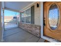 Inviting front porch with a wooden door and a white railing at 1420 Hickory Dr, Erie, CO 80516