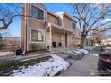 Tan two-story townhome with snowy landscaping and small front porch at 1818 S Quebec Way # 13-2, Denver, CO 80231