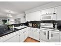 Modern white kitchen with black countertops and stainless steel appliances at 1818 S Quebec Way # 13-2, Denver, CO 80231