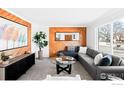 Bright living room featuring a cozy sectional sofa, wood wall accents, and large windows at 399 Jackson Cir, Louisville, CO 80027