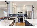 Modern kitchen featuring white cabinets, stainless appliances, a double sink and stylish blue subway tile backsplash at 6646 Bean Mountain Ln, Boulder, CO 80301