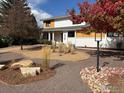 Landscaped front yard with a modern walkway and mature trees at 6969 Harvest Rd, Boulder, CO 80301