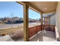 Covered porch with wooden railing, offering a view of the neighborhood at 724 Widgeon Cir, Longmont, CO 80503