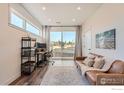 Cozy living room featuring a comfortable leather sofa, large windows, and a modern work space at 2446 W 167Th Ln, Broomfield, CO 80023
