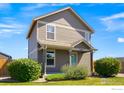 Two-story house with light brown siding, teal door, and landscaping at 3088 Rose Hill St, Strasburg, CO 80136