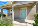 Covered porch with teal door and blooming flowers at 3088 Rose Hill St, Strasburg, CO 80136