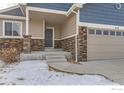 Inviting front entrance with stone pillars, a covered porch, and a two-car garage at 413 Canyonlands St, Berthoud, CO 80513