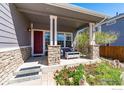 Covered porch with stone pillars, seating area, and landscaping at 909 Glenarbor Cir, Longmont, CO 80504