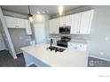 Modern kitchen with white cabinets, stainless steel appliances, and a quartz countertop island at 2303 Peregrine Dr, Brighton, CO 80601