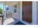 Covered front porch with brown door and railing at 2437 Bristol St, Superior, CO 80027