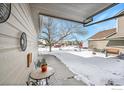 Covered patio with sitting area, overlooking a snowy yard at 421 Stevens Cir, Platteville, CO 80651