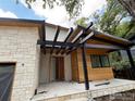 A modern home entrance featuring a stone wall, black pergola, and light wood siding at 2250 Bluebell Ave, Boulder, CO 80302