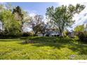 A lush backyard with mature trees, a fire pit, and a sunroom addition to the home at 4667 Ashfield Dr, Boulder, CO 80301